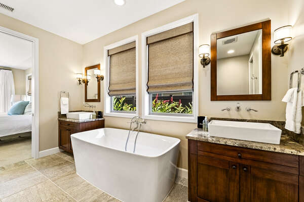 The main en-suite bathroom of this  Holua Kai at Keauhou rental is complete with a large tub and two vanity sinks.