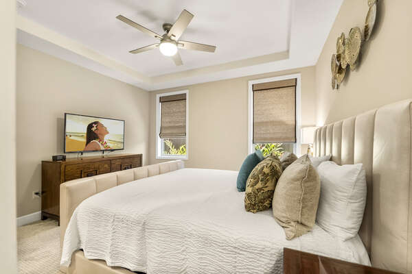 A TV sits on the dresser at the foot of the king bed of Bedroom 2.