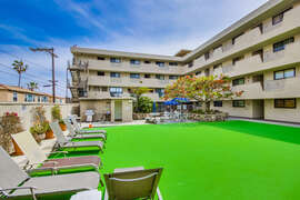 Sun deck located adjacent to swimming pool on main level of building, equipped with loungers and BBQ