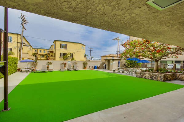 Sun deck located adjacent to swimming pool on main level of building, equipped with loungers and BBQ