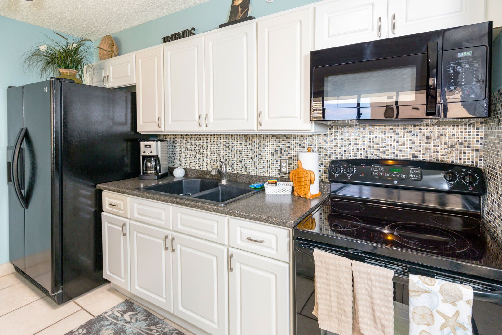Fully equipped kitchen with toaster, coffee maker, rice cooker, blender, kettle, pots, pans, silverware, cookware, dishes.