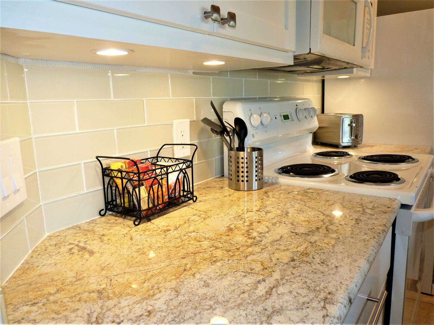 There's lovely glass, subway tile all along the back splash and the under-the-counter lights are such a nice touch!