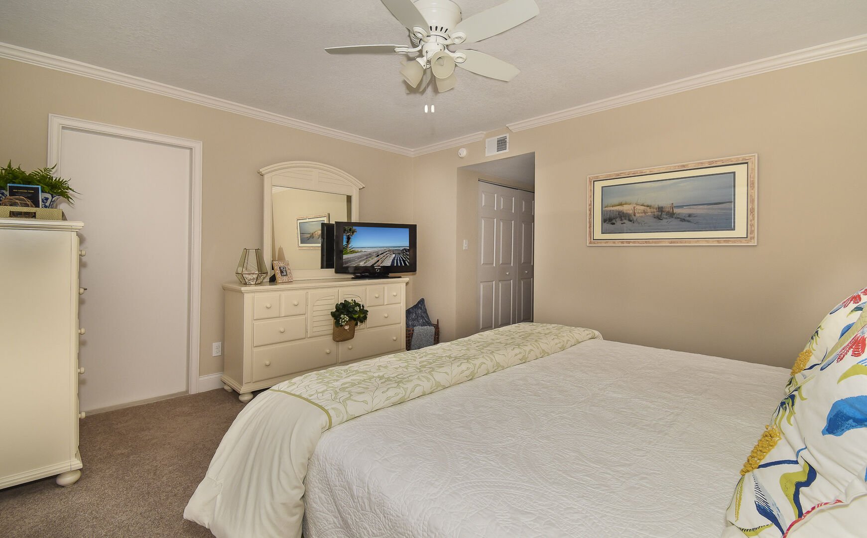 Bedroom with large bed, smart TV, ceiling fan, and dresser