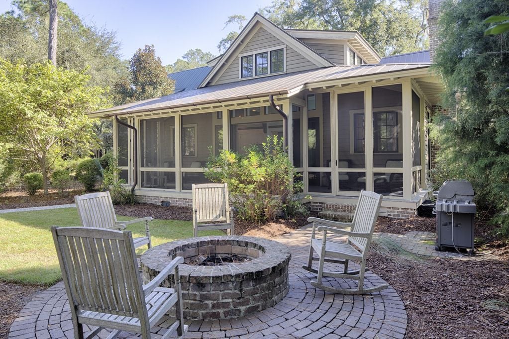 Steps from the large screened in porch are the fire pit area and gas grill