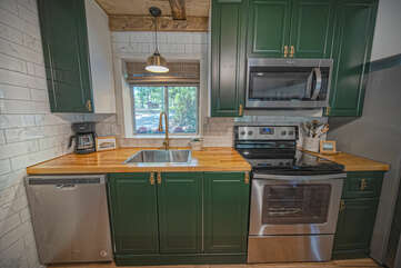 Stainless steel appliances in the kitchen surrounded by green painted cabinetry.