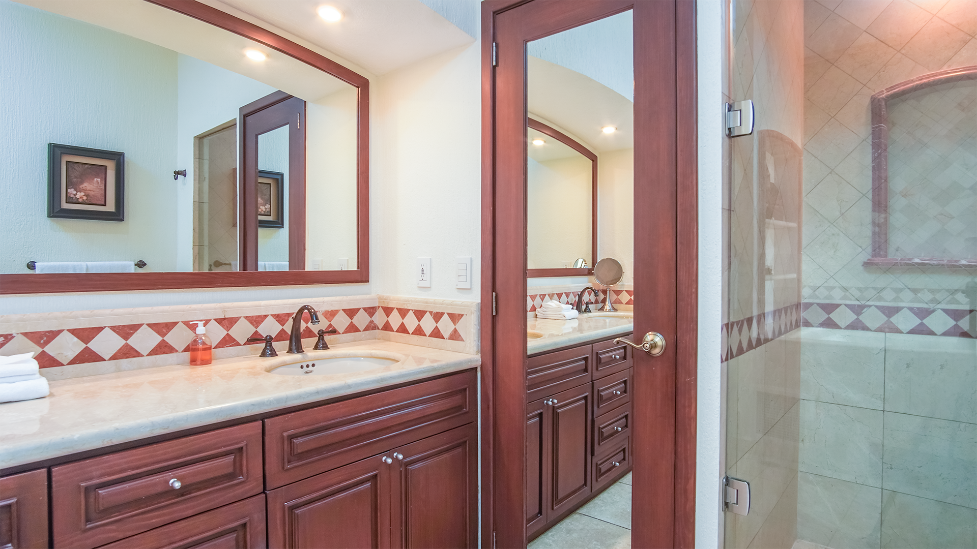 The master bathroom with marbled counter, glass enclosed shower, and elegant wood trim.