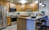 Kitchen with light wood cabinets, built-in appliances, peninsula with two stools.