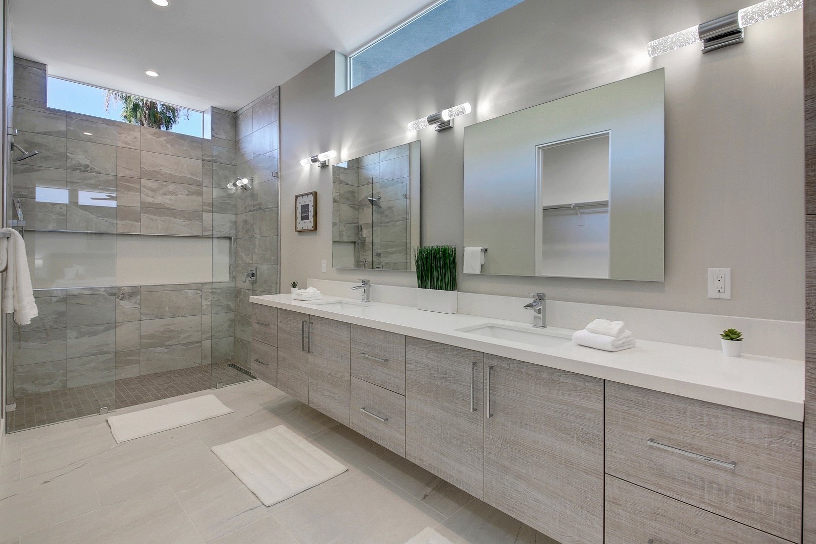 Private, en suite bathroom features a tile shower with double shower heads and two vanity sinks.