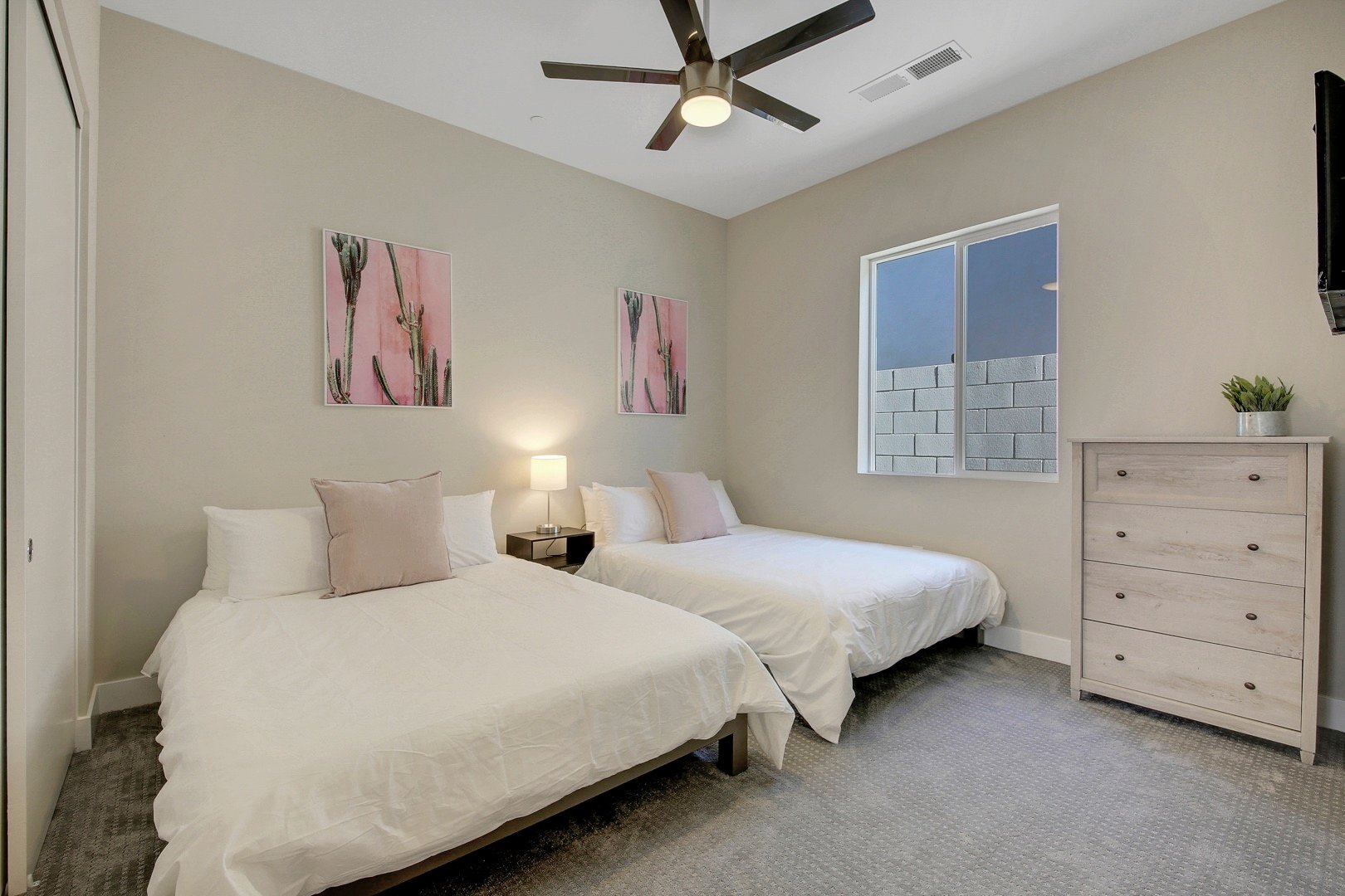 Bedroom 2 is located next to the Master Suite and features two Queen-sized Beds, 32-inch Insignia Fire-TV Smart television, and access to the hallway bathroom.