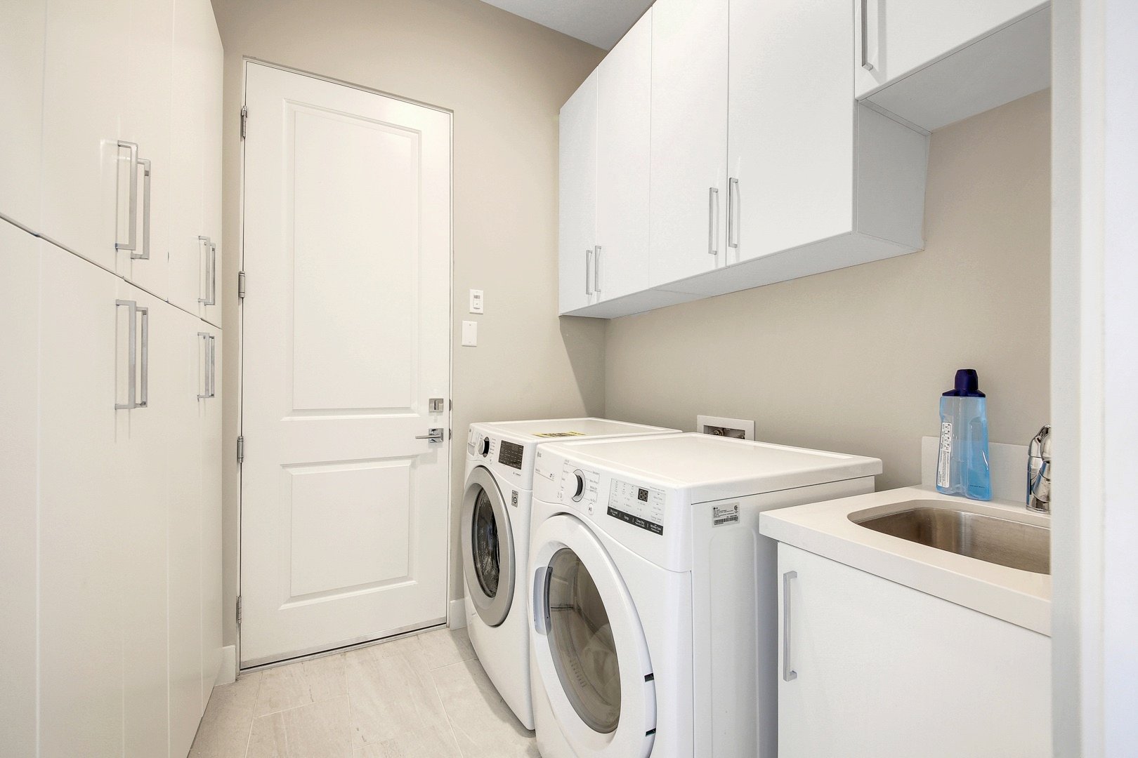 Fully equipped laundry room with washer, dryer, ironing board, and iron.