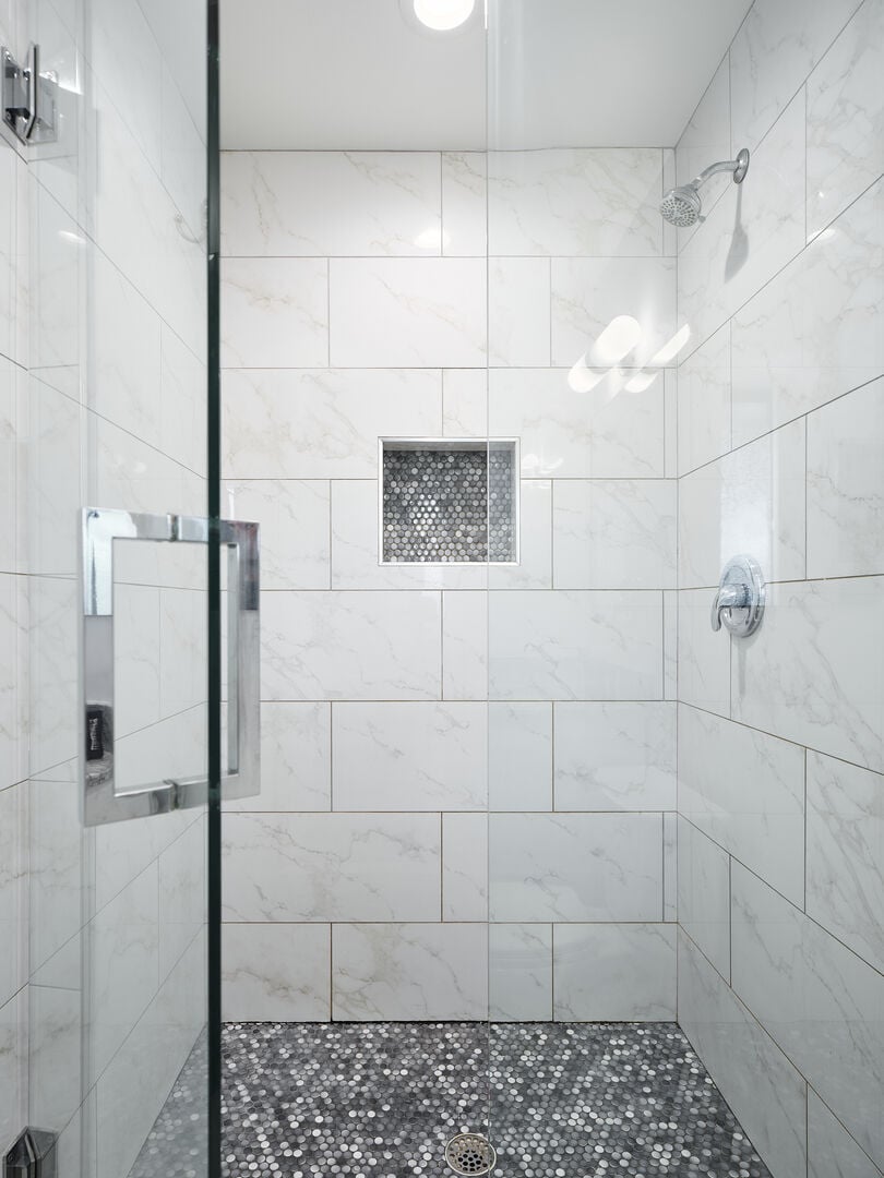Primary bathroom with walk-in tiled shower.