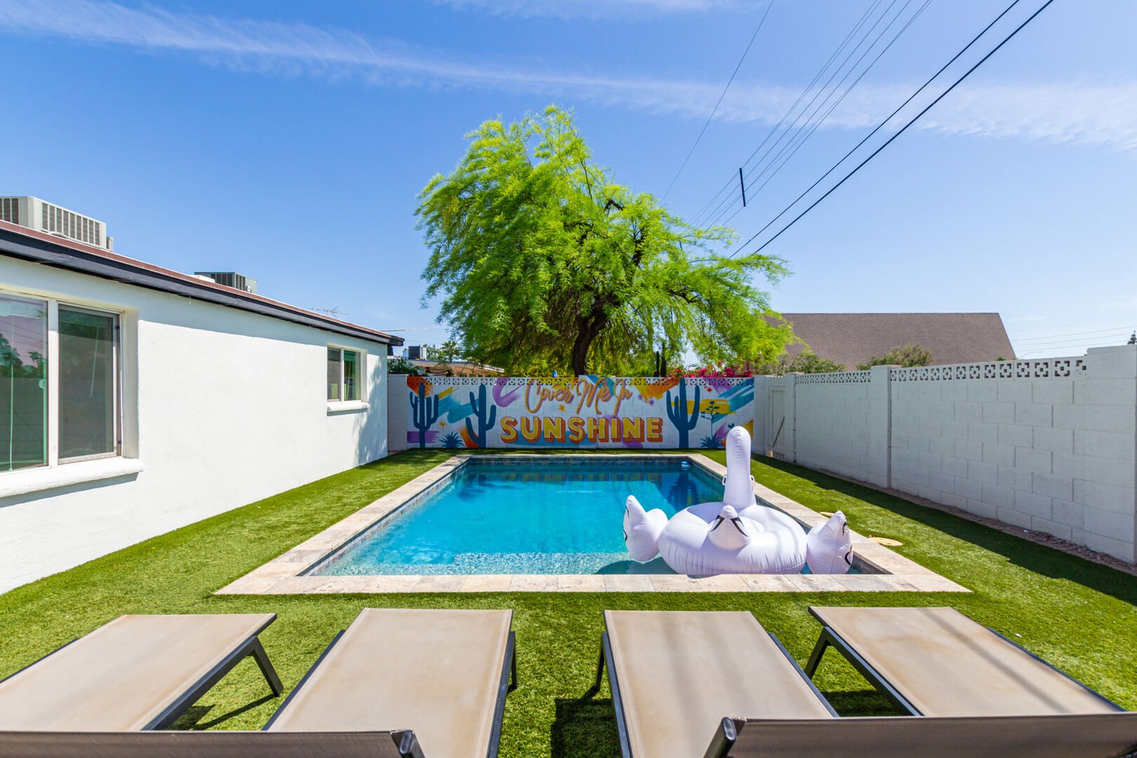 Private Backyard featuring a new mural, sparkling blue pool, fire pit, yard games and a covered patio with outdoor dining and lounging.