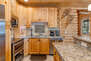 Kitchen Area with Stone Countertops, Island Seating for Two, Stainless Steel Appliances, and Double-Oven