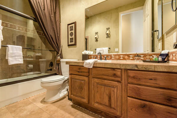 Full Shared Bathroom with a Stone Counter Sink and a Tub/Shower Combo