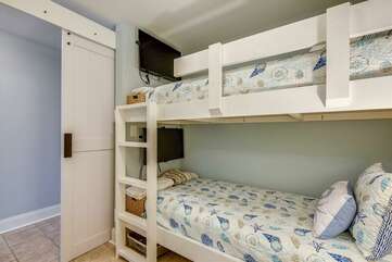 Private bunk area with sliding barn door. Both twin beds have mounted TVs for children to use,