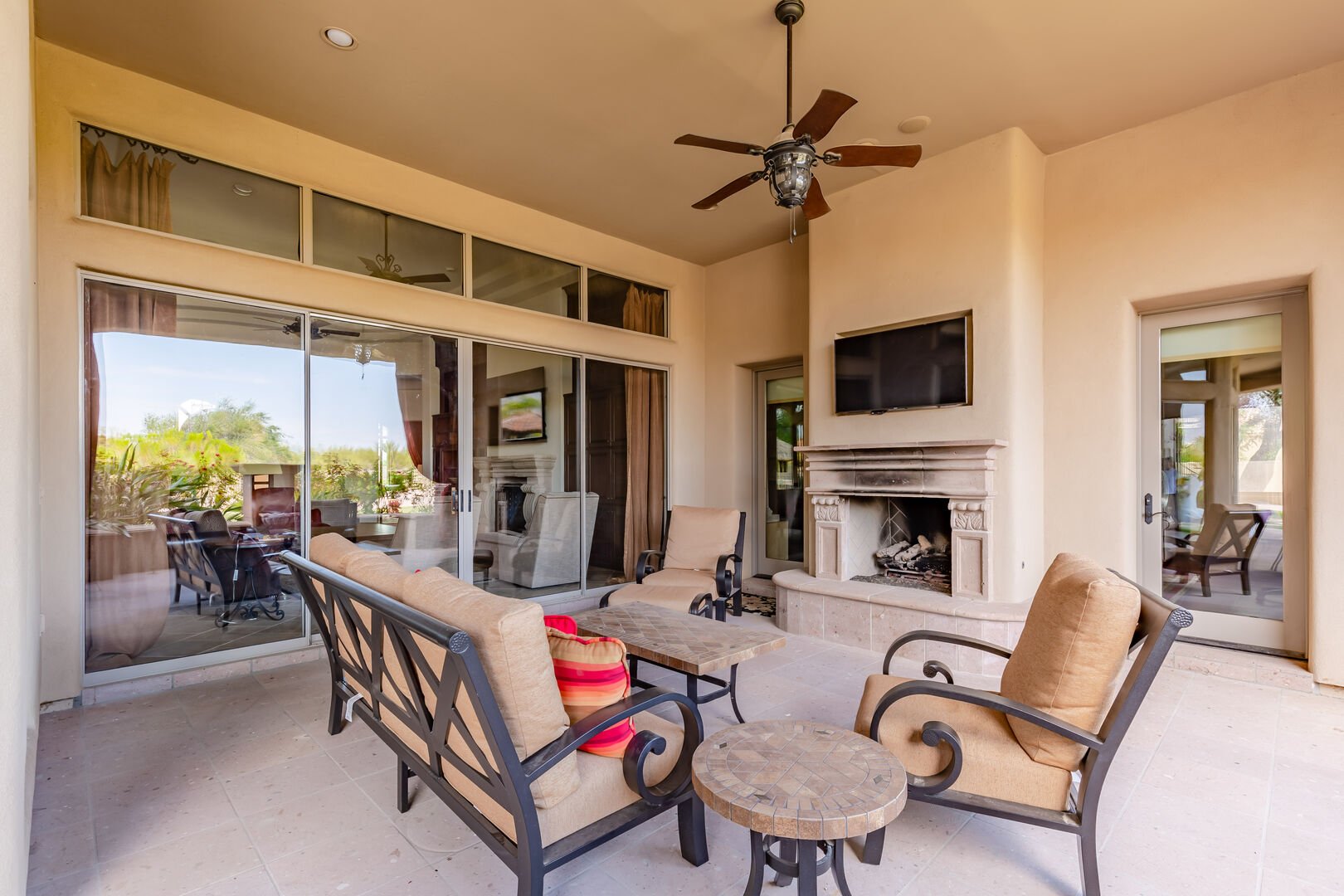 Backyard covered patio featuring an outdoor fireplace accompanied by a Smart TV and outdoor furnishings for relaxing.
