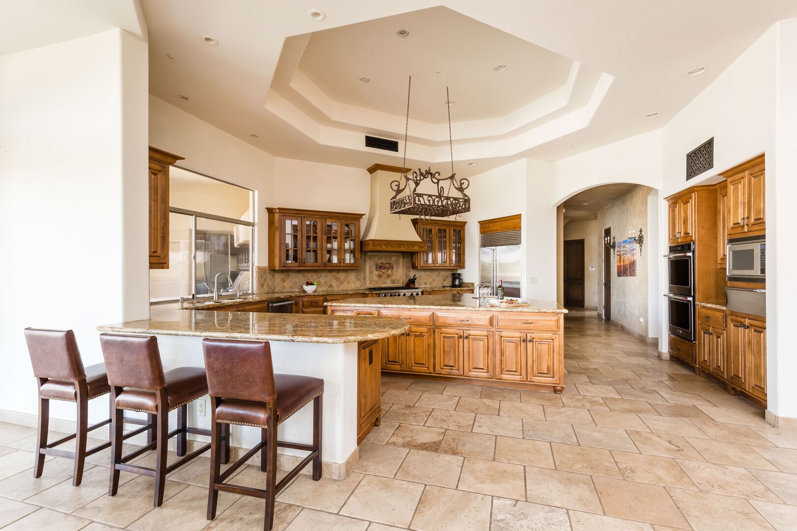 The kitchen is a chef's dream, with stainless-steel appliances, a large island with ample counter space, double oven, bar seating, and stocked with all culinary essentials.