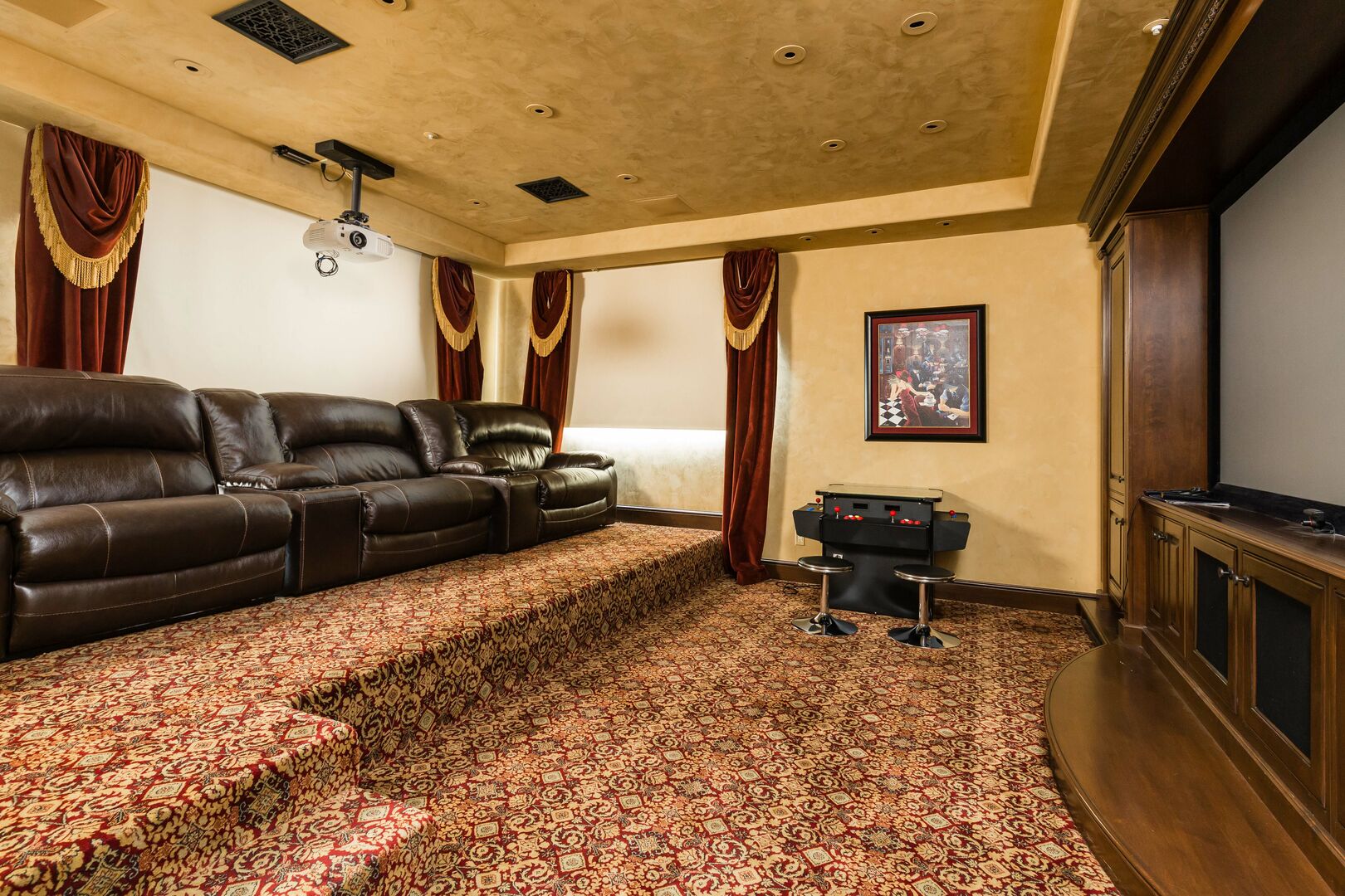 Movie Theatre room with a large projector and screen, comfortable movie recliners and classic arcade games.