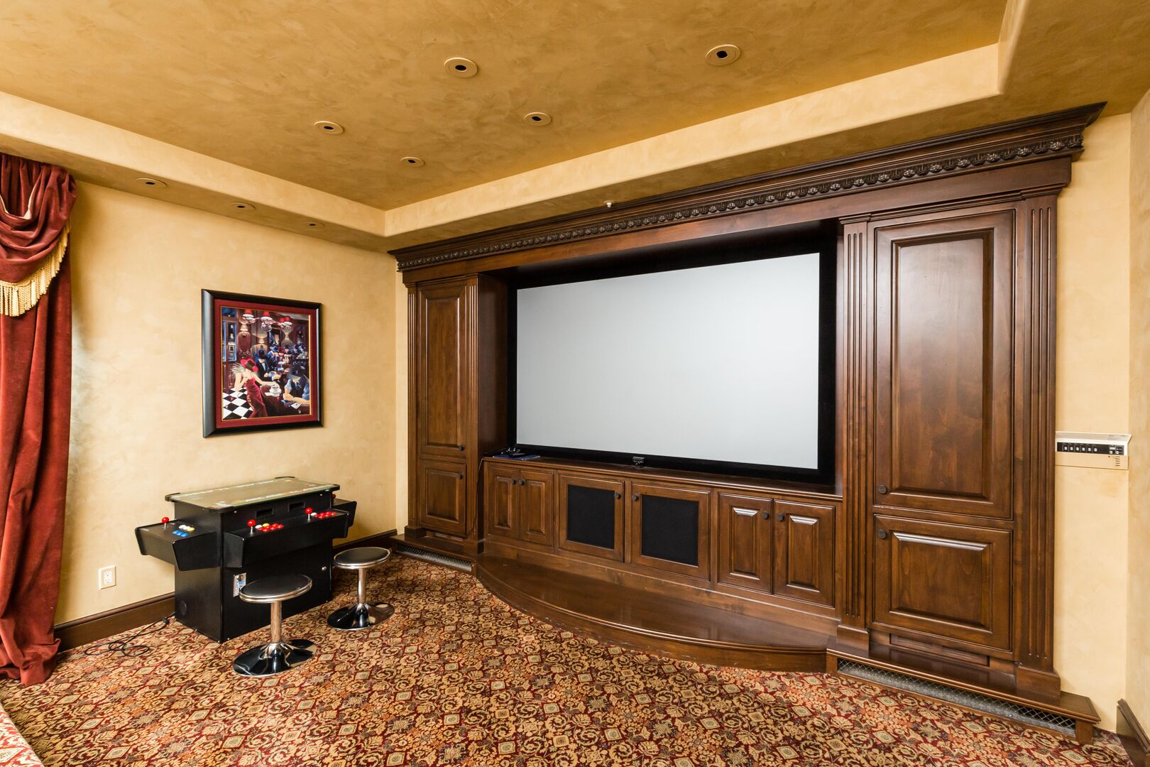 Movie Theatre room with a large projector and screen, comfortable movie recliners and classic arcade games.