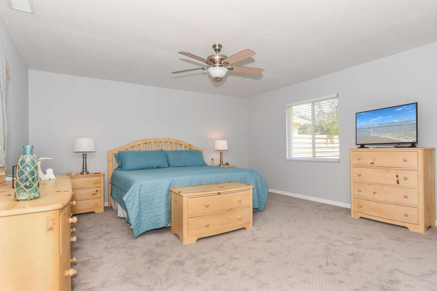 spacious bedroom with tv and furniture inside new smyrna beach home rental