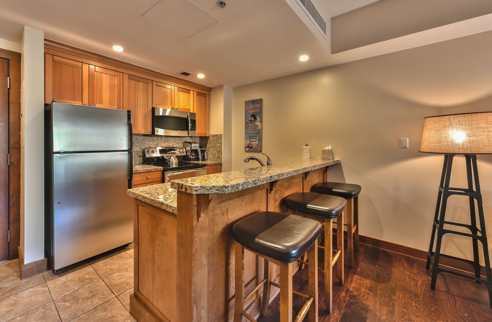Kitchen featuring granite and stainless steel, barstools for three