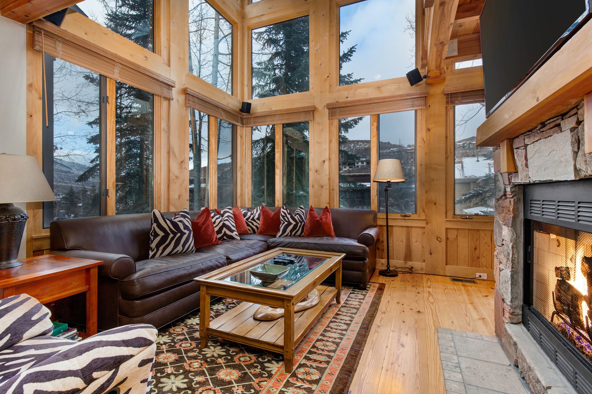 Living Room with vaulted ceilings, stunning windows that allow for an abundance of natural light, leather furnishings, full sofa-bed, gas fireplace, and 55