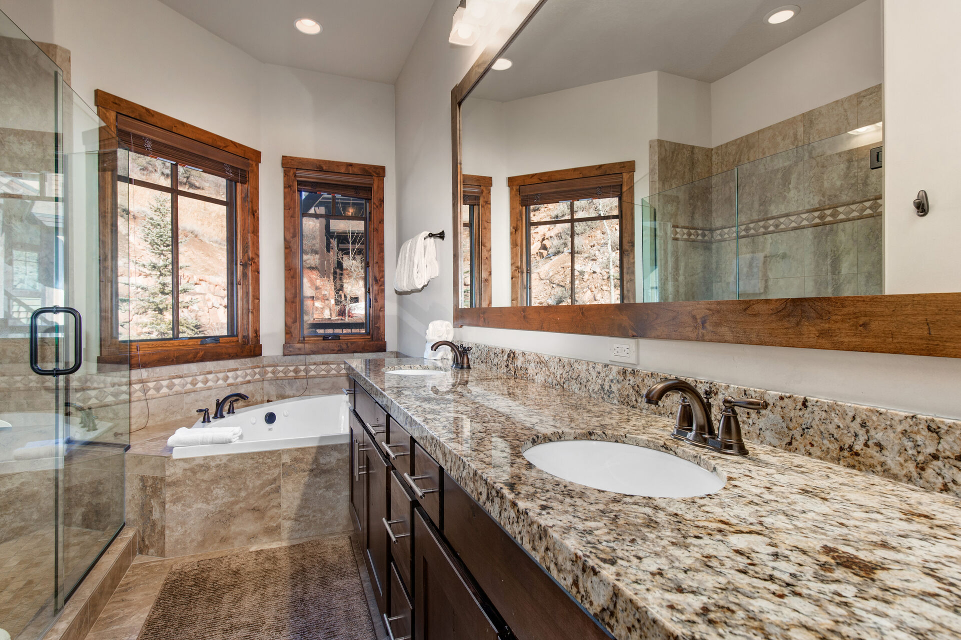 Master Bathroom with dual sinks, stone countertops, jetted tub, and large tile shower