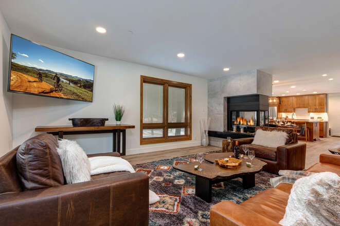 Living room with sleeper sofa, wet bar and beverage fridge, two-sided Gas Fireplace and 65