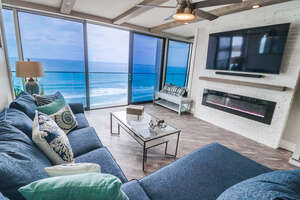 Living room with a queen size sofa bed, ceiling fan, fireplace, Smart TV, dining area for 4, and an ocean view
