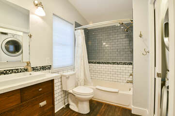 Single Vanity Sink, Lamps, Mirror, Toilet, and Shower-Tub Combo.