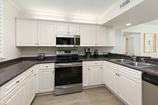 The open Kitchen has stainless steel appliances and crisp, white cabinets.