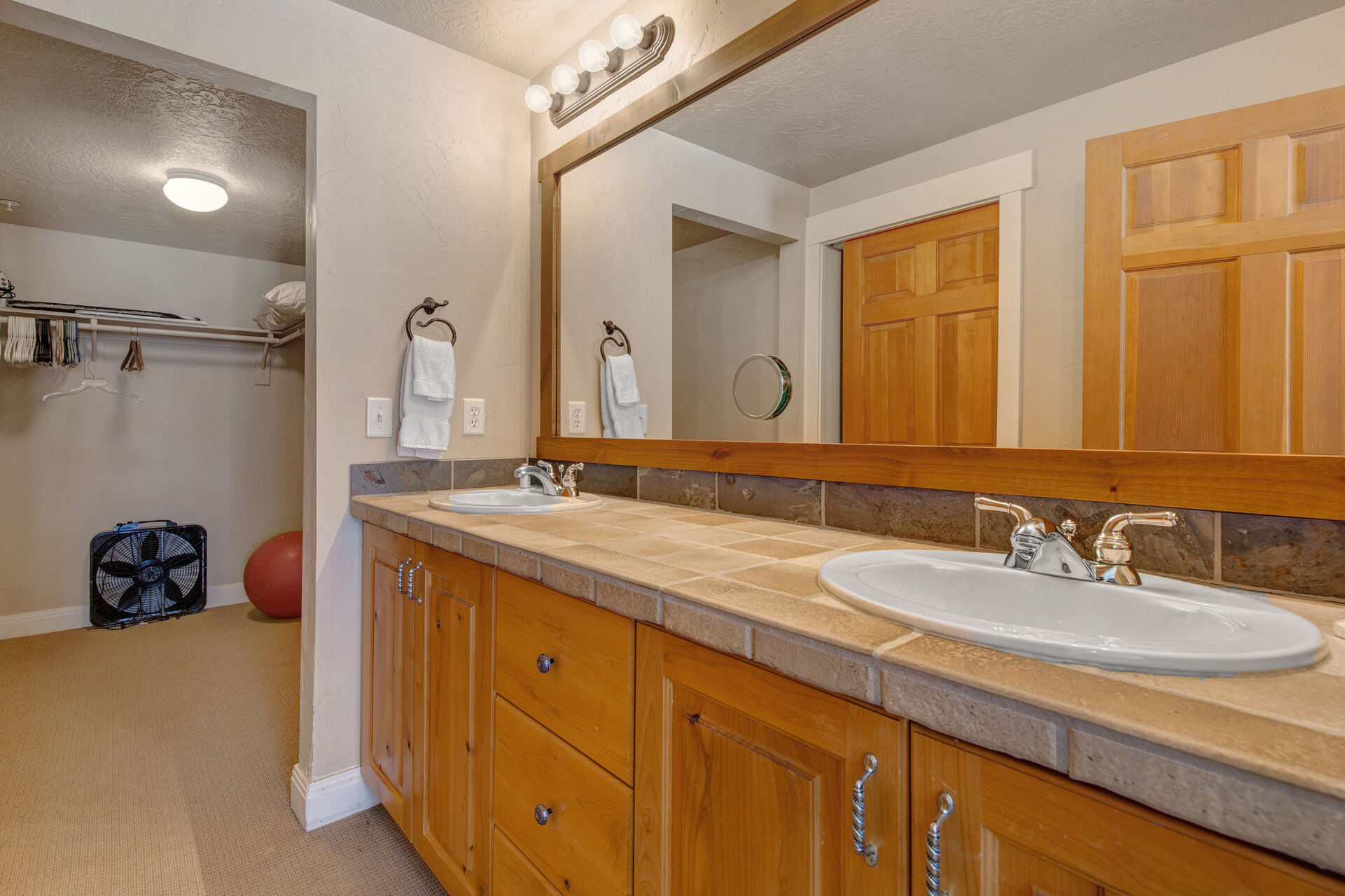 Master Bathroom with dual vanities, walk-in closet, large soaking tub, and separate tiled shower