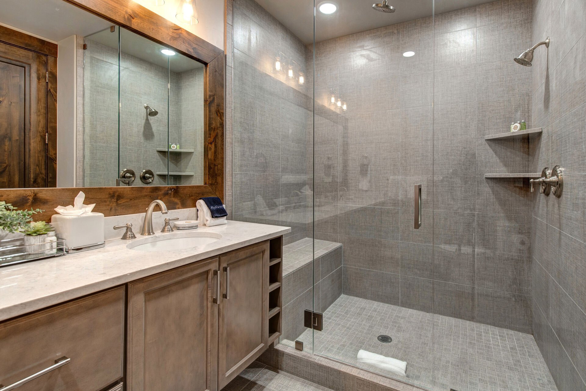 Master Bathroom with dual vanities and over-sized tile shower that has built-in seating and shelving