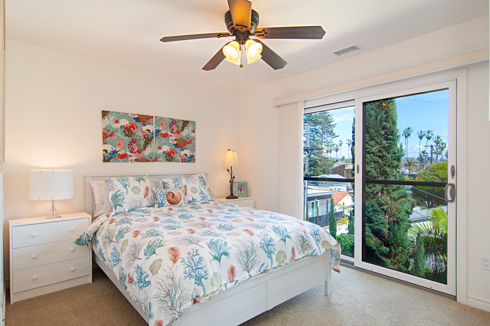 Upstairs guest bedroom with queen bed, ceiling fan and private balcony