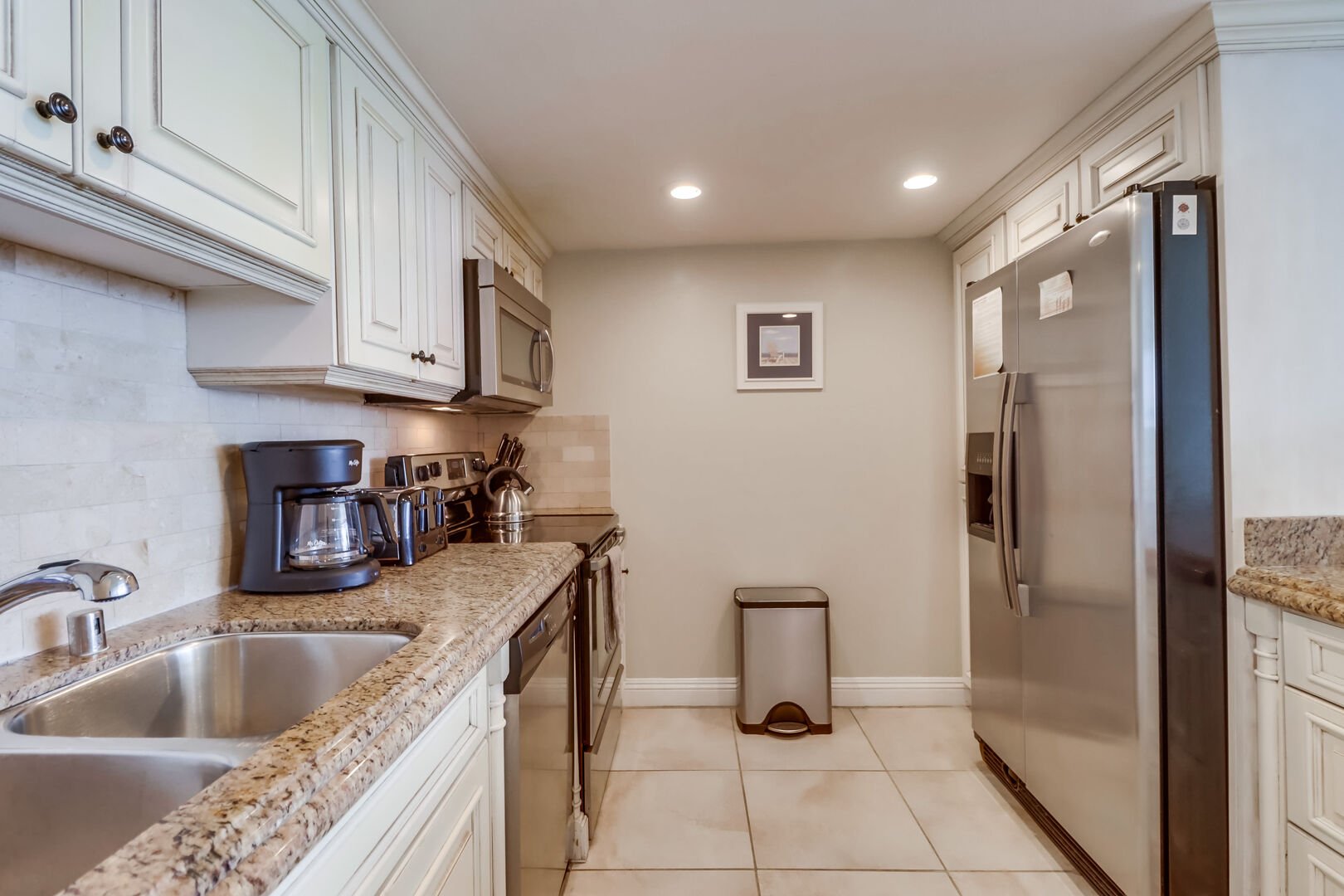Fully equipped kitchen with stainless steel appliances including a dishwasher, standard coffee maker, oven and gas stove, toaster and large refrigerator with water filtration and freezer with ample storage.