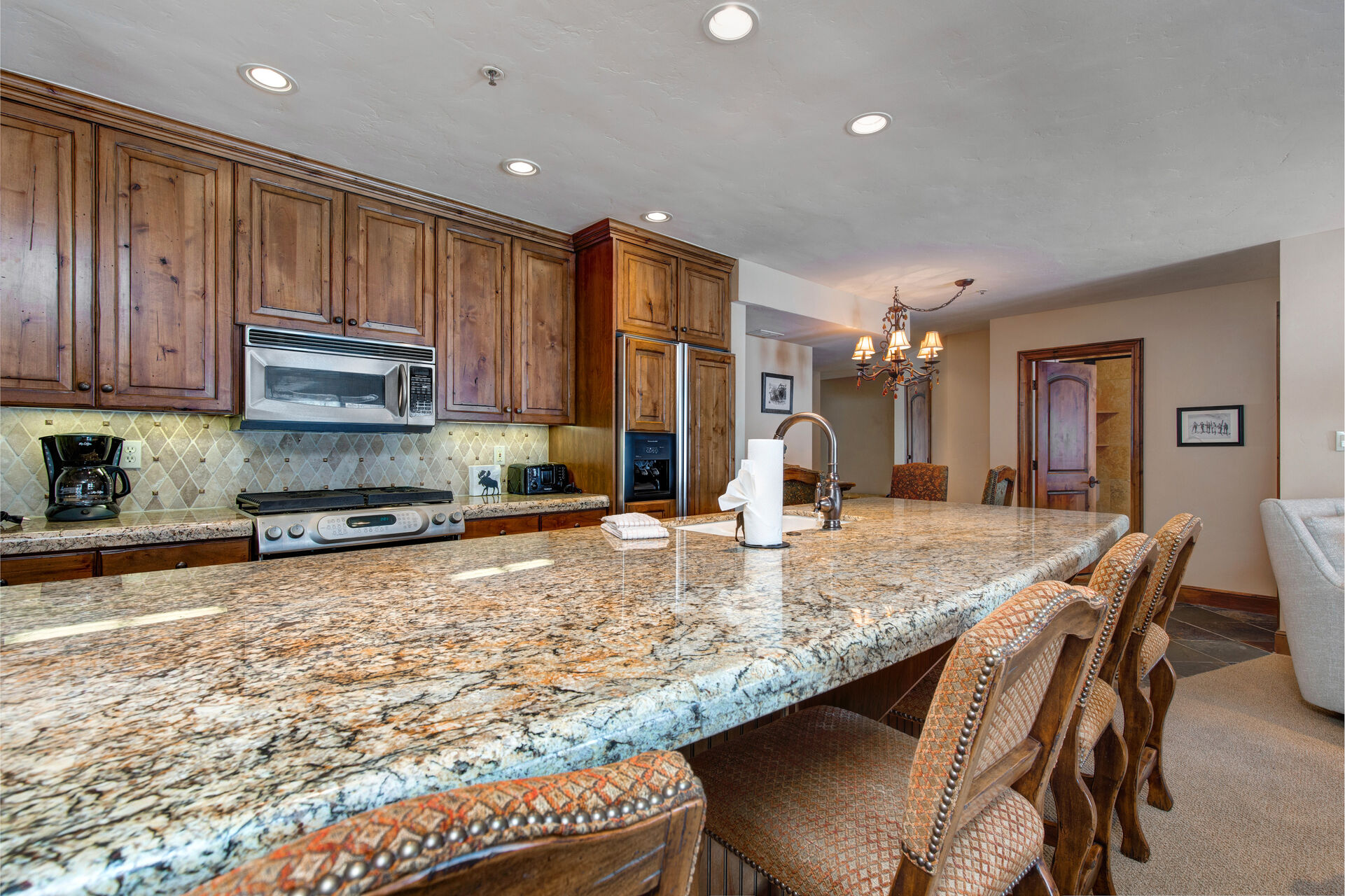 Fully Equipped Kitchen with beautiful stone countertops, stainless steel appliances, ample space, built-in water and ice dispenser, and bar seating for four