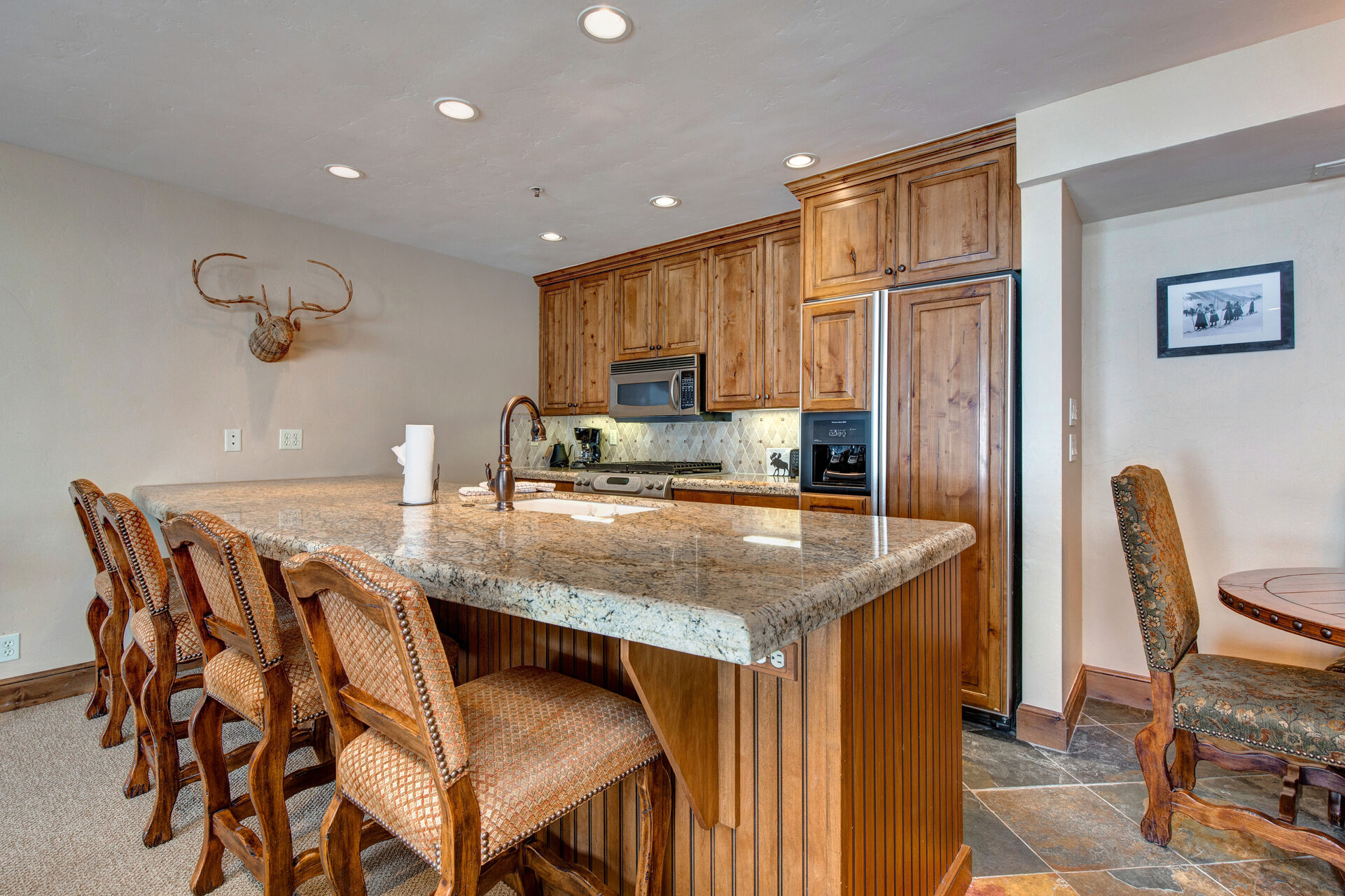 Fully Equipped Kitchen with beautiful stone countertops, stainless steel appliances, ample space, built-in water and ice dispenser, and bar seating for four