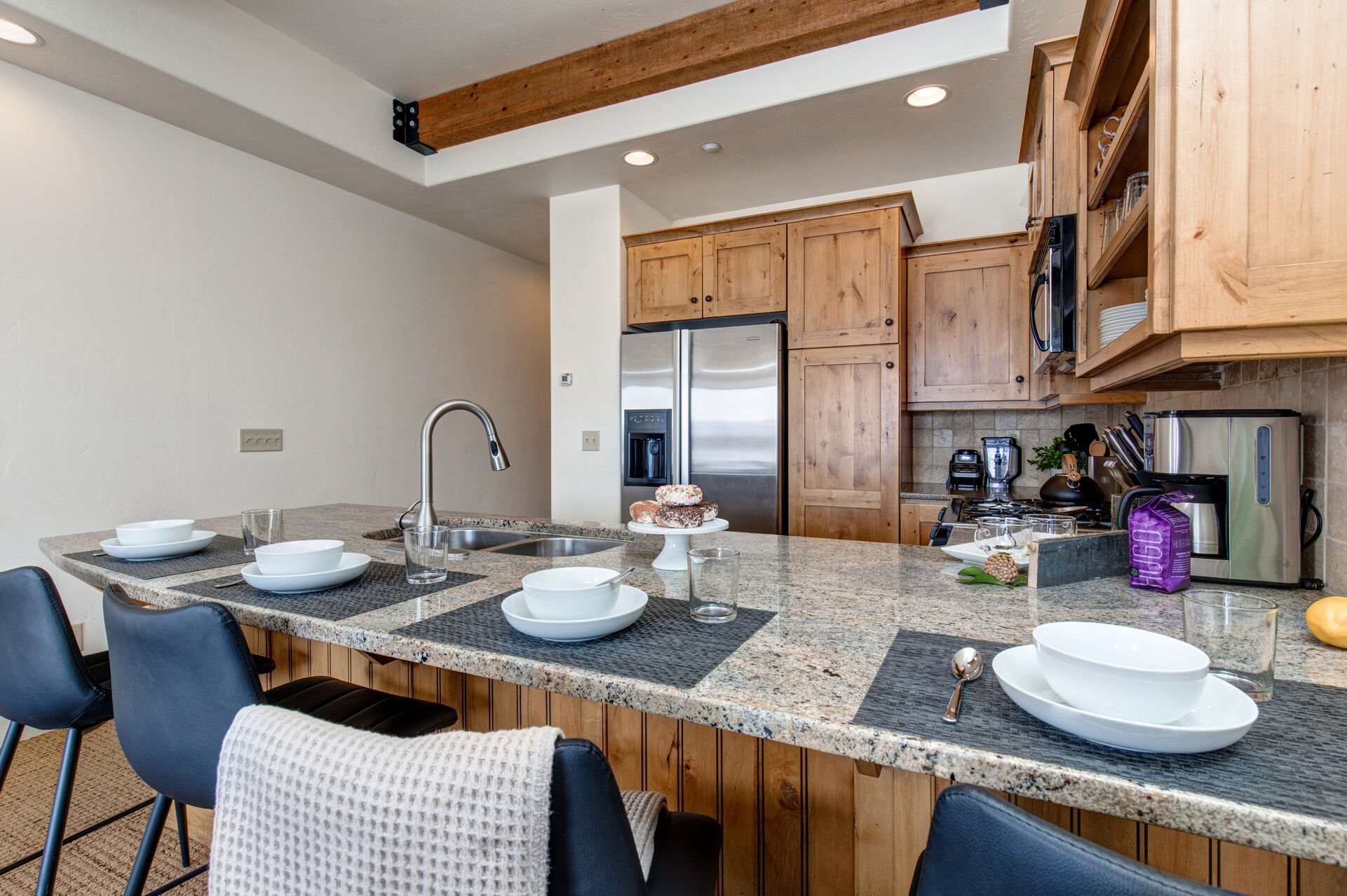 Fully Equipped Kitchen with granite countertops, stainless steel appliances, built-in water and ice dispenser, and bar seating for four