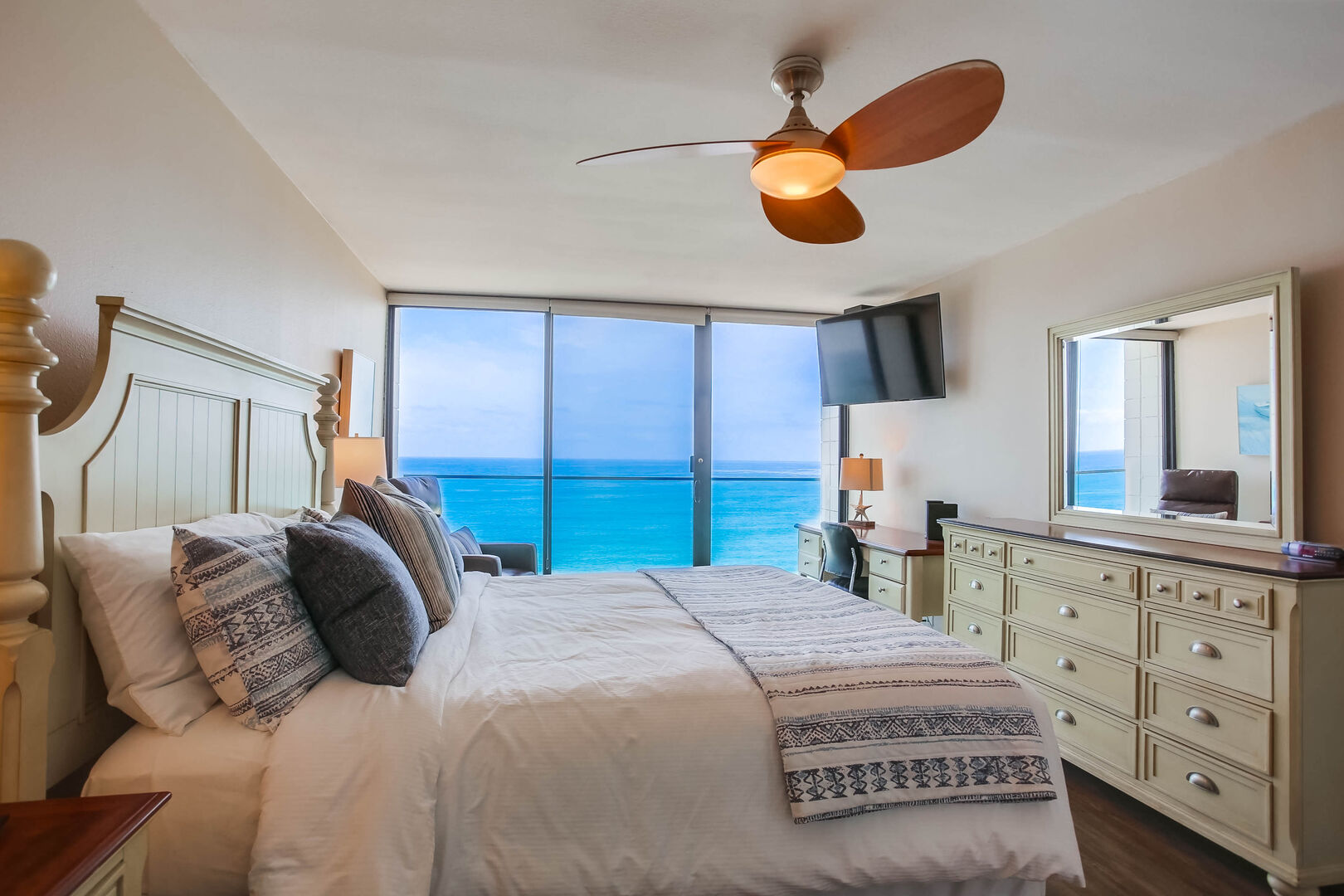Master bedroom with dresser, ceiling fan, king size bed, dressers, TV and an ocean view