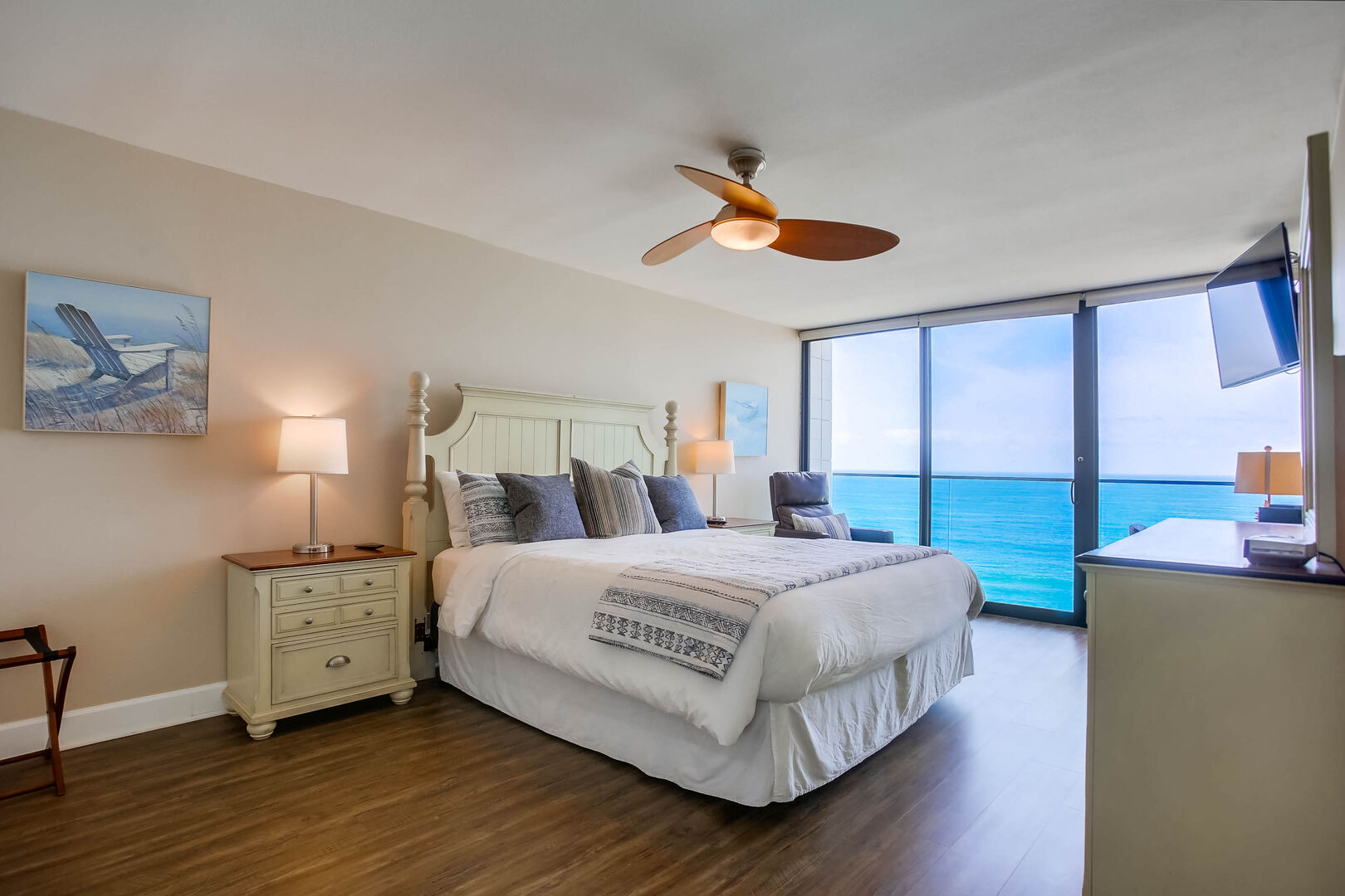 Master bedroom with dresser, ceiling fan, king size bed, dressers, TV and an ocean view