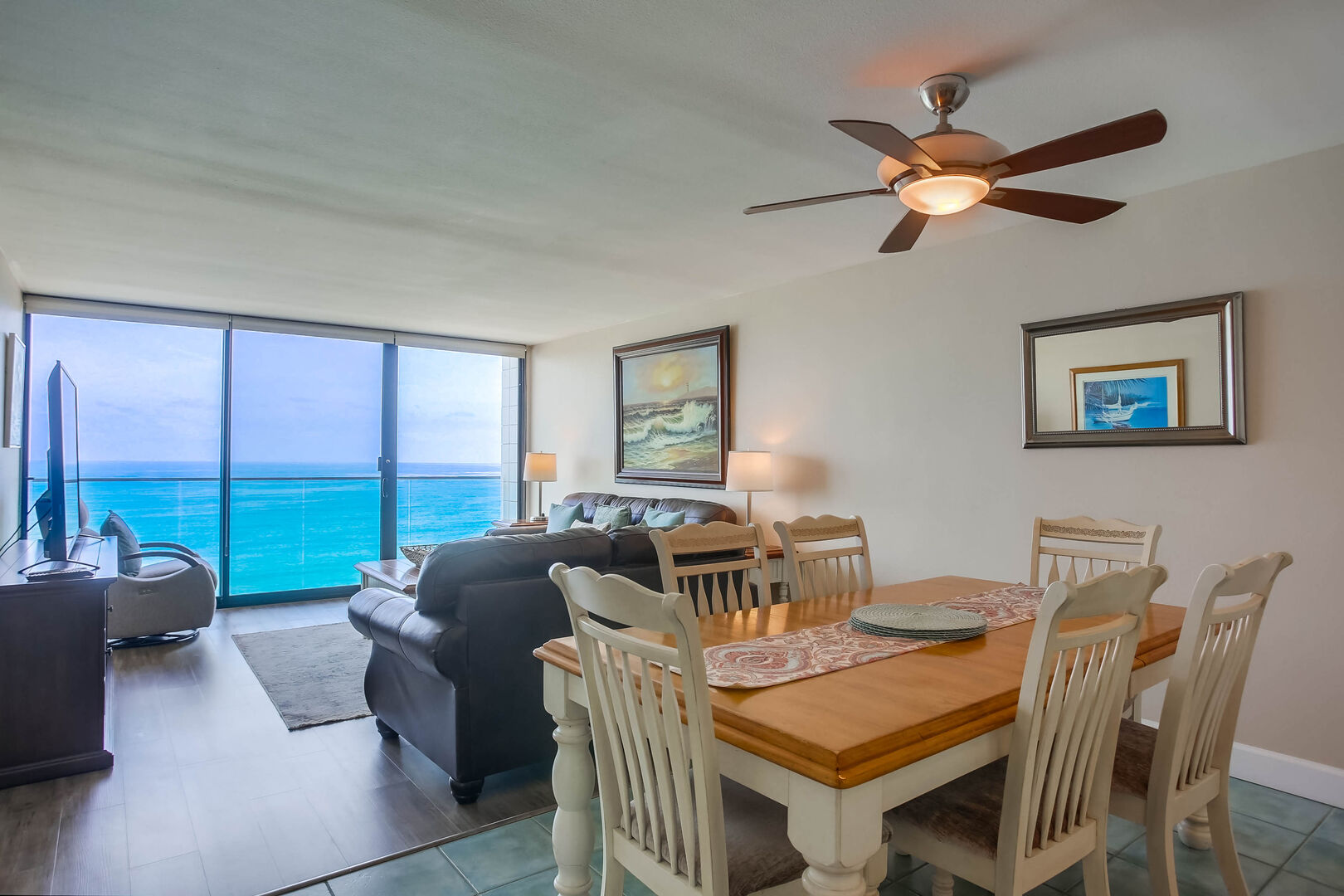 Open style floor plan with living room, dining seating for 6, ceiling fan, and an ocean view