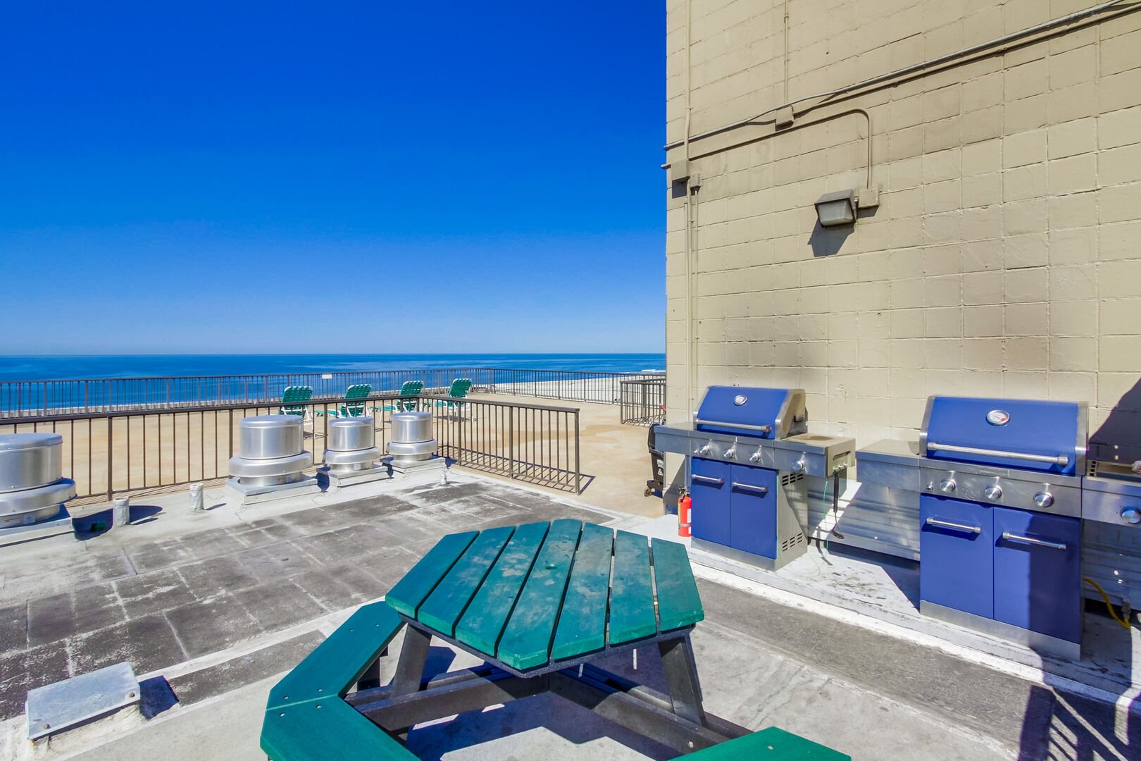 Community rooftop deck with oceanfront view, lounge chairs, BBQ