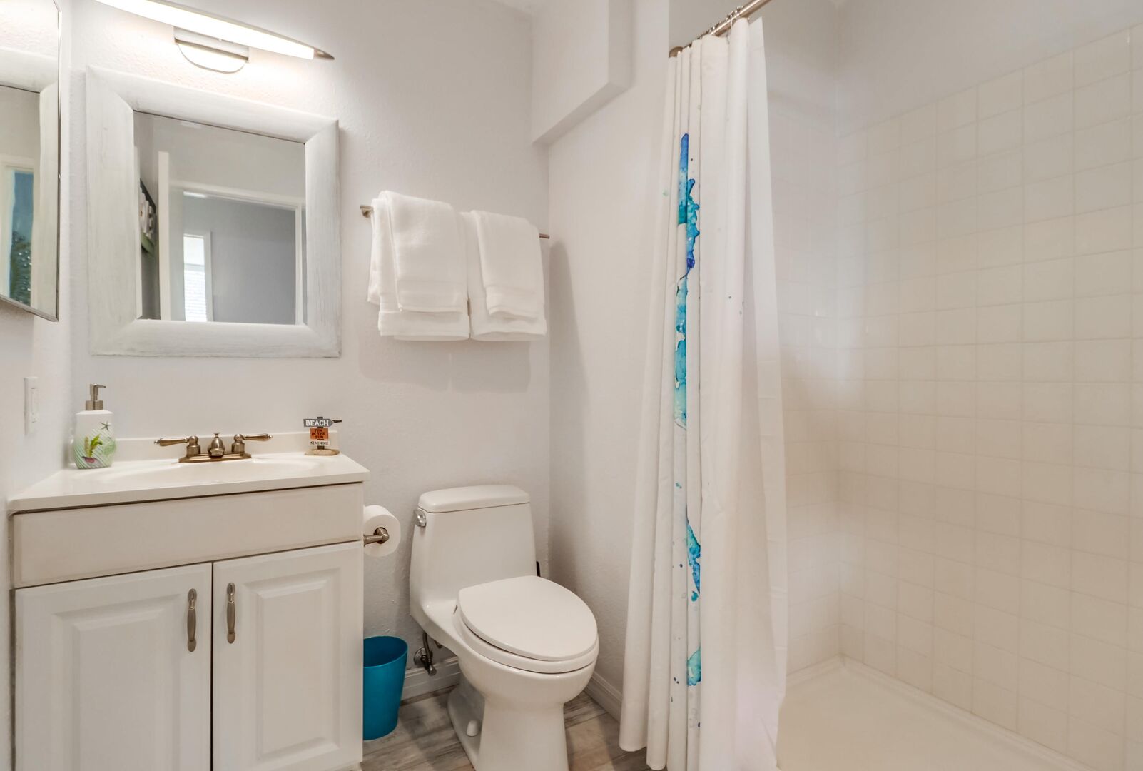 Guest bathroom with walk-in shower, vanity, toilet and cabinet and drawer space