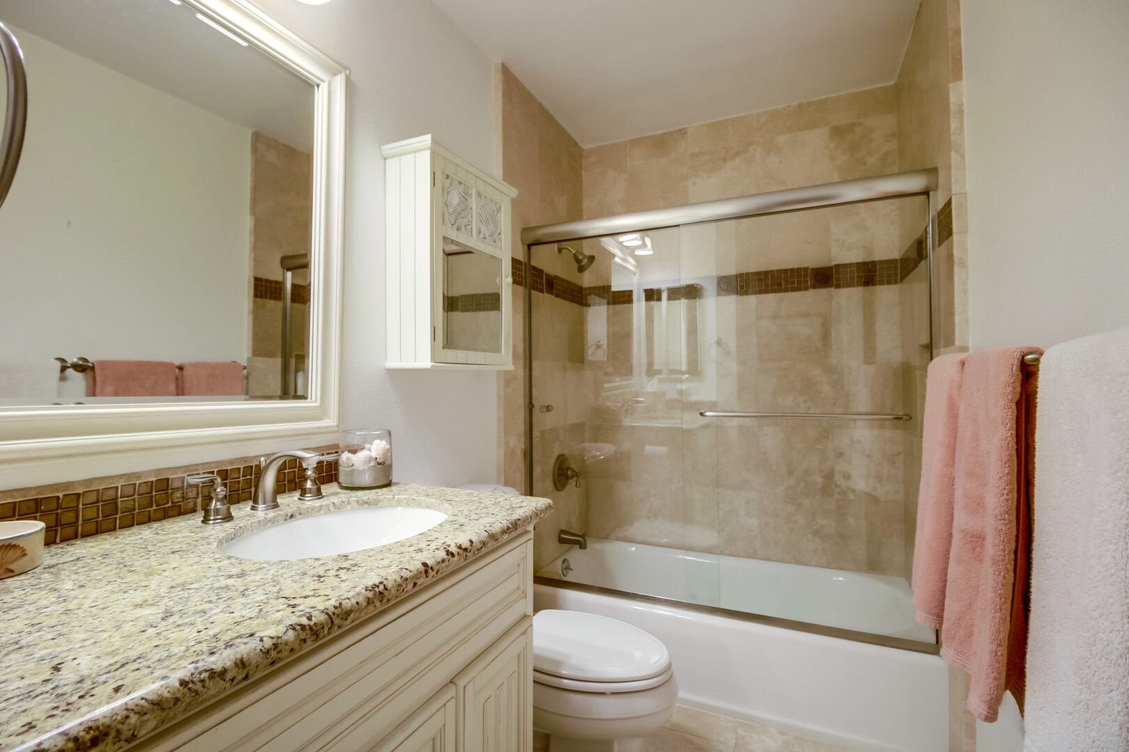 Guest bathroom with a shower/tub combo, large vanity, toilet and cabinet and drawer space