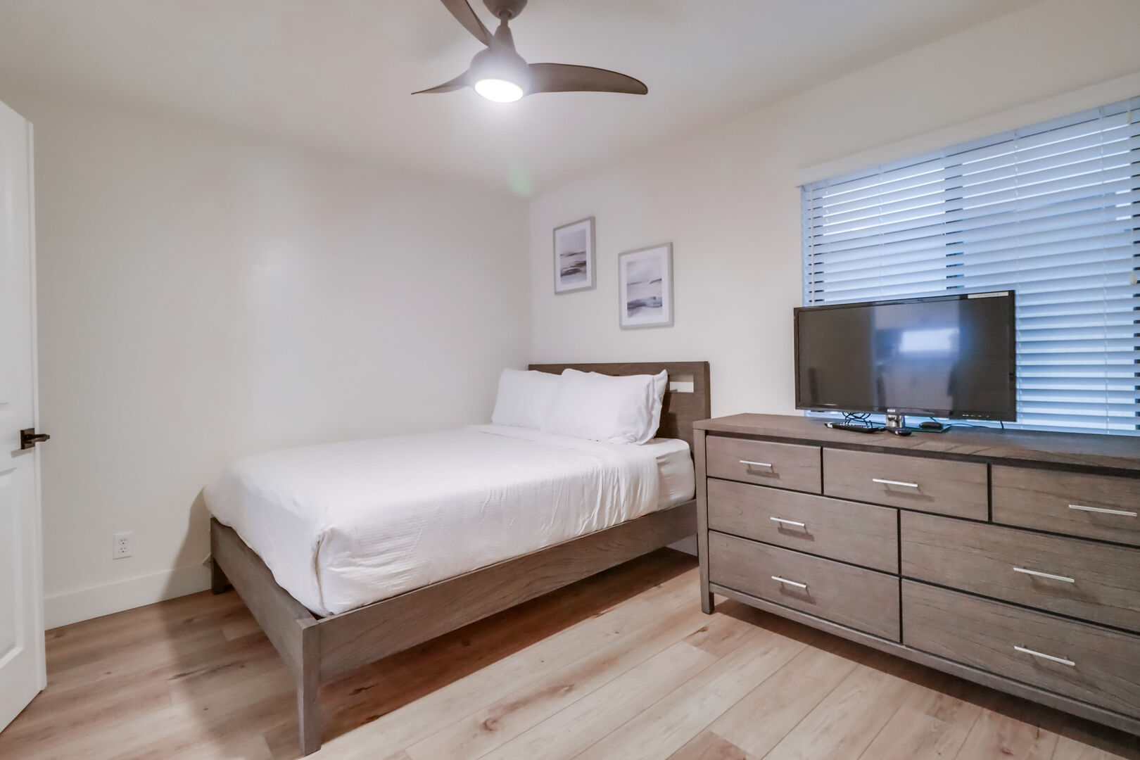 Guest bedroom, first bedroom from the living space, with a queen bed, dresser, ceiling fan, closet and Smart TV