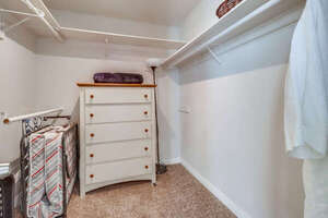 Large walk-in closet with portable fans, hangers, additional dresser and shelf space