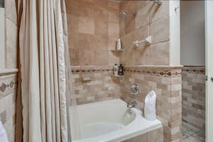 In-suite full bathroom with a shower-tub combo (and toilet to the right)