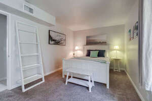 Second guest bedroom across from the master bedroom with a queen bed, shelves, night stands, and mirrored large closet