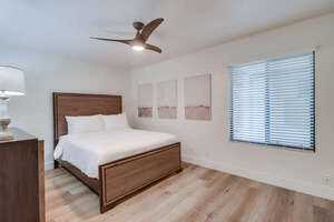 Guest bedroom adjacent to the master suite with queen bed, ceiling fan, mirrored closet and dresser storage