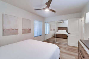 Guest bedroom across from the master suite with queen bed, ceiling fan, mirrored closet and dresser